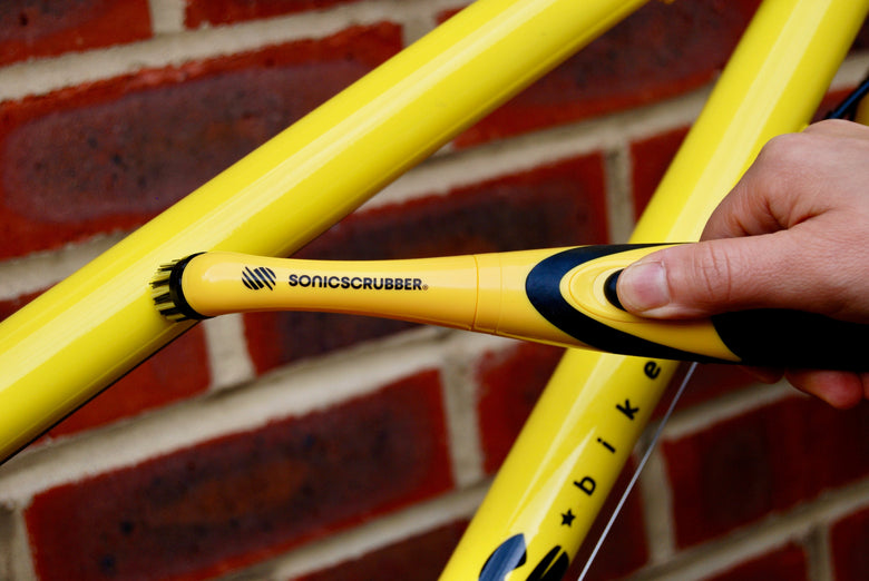Yellow SonicScrubber cleaning a yellow bike frame